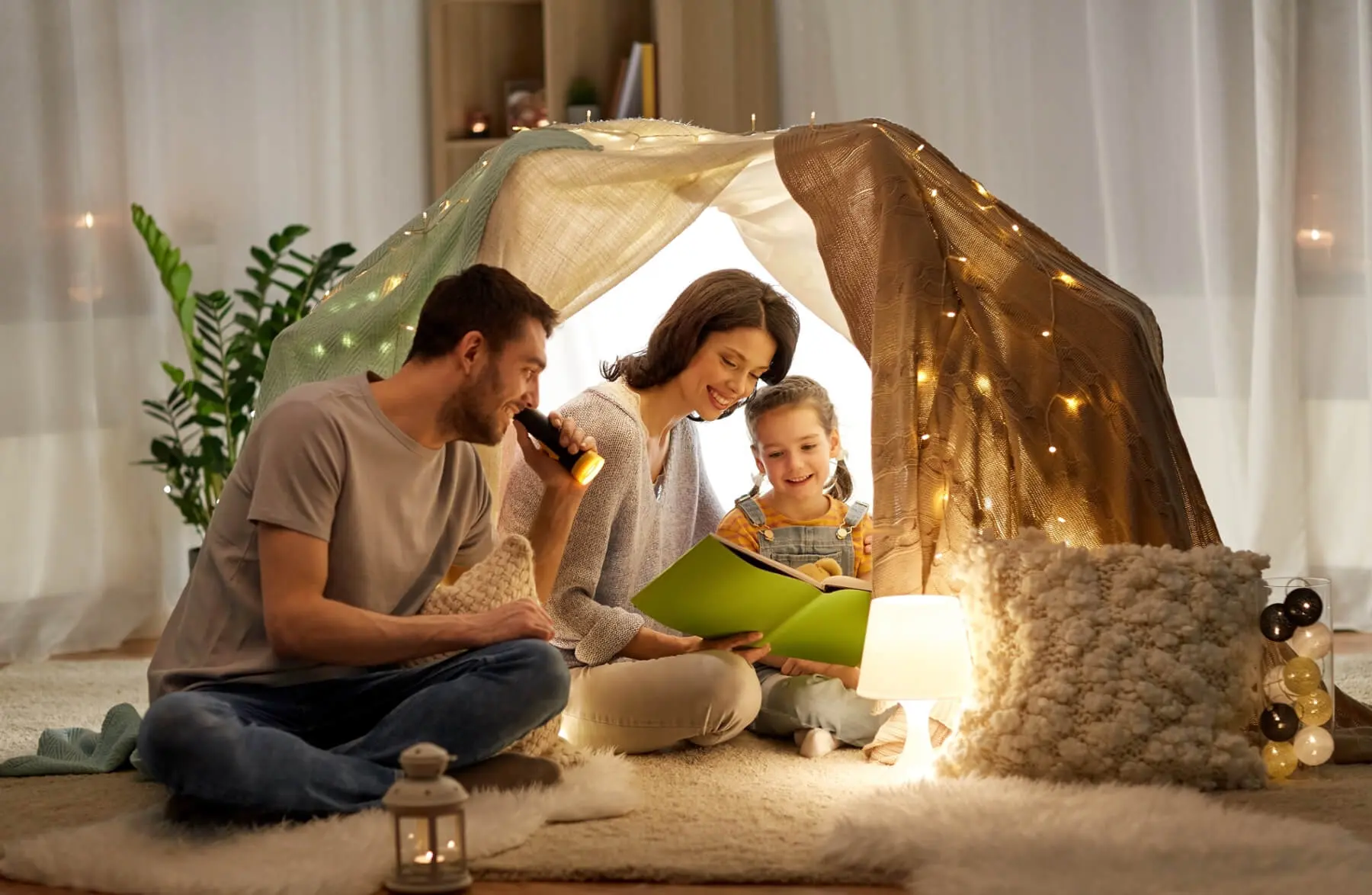 A family sitting on the floor in front of a tent.